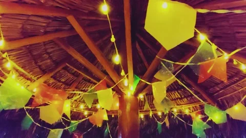 Festive party flags and string lights on a rustic thatched roof. June. Stock Footage 313240908