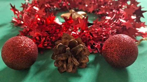 Festive pine cone with red glitter ornaments on green background Stock Photos
