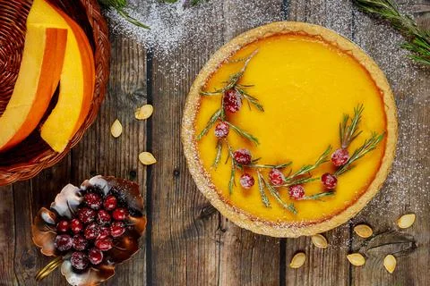 Festive pumpkin pie with cranberry on rustic background, top view. Stock Photos