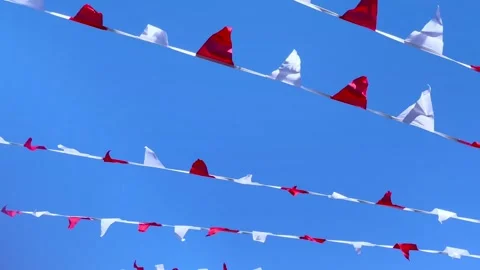 Festive red and white triangular flags moving in the wind against a blue sky. Stock Footage 241904857