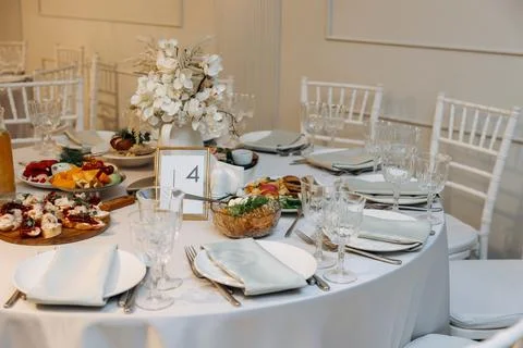 Festive round banquet table setting with table number four, food platters 库存照片