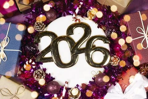 A festive round cake features bold metallic 2026 digits surrounded by purple tin Stock Photos