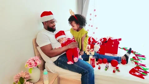 A festive scene featuring a father in a Santa hat holding a child with daughter. Video stock 295920189