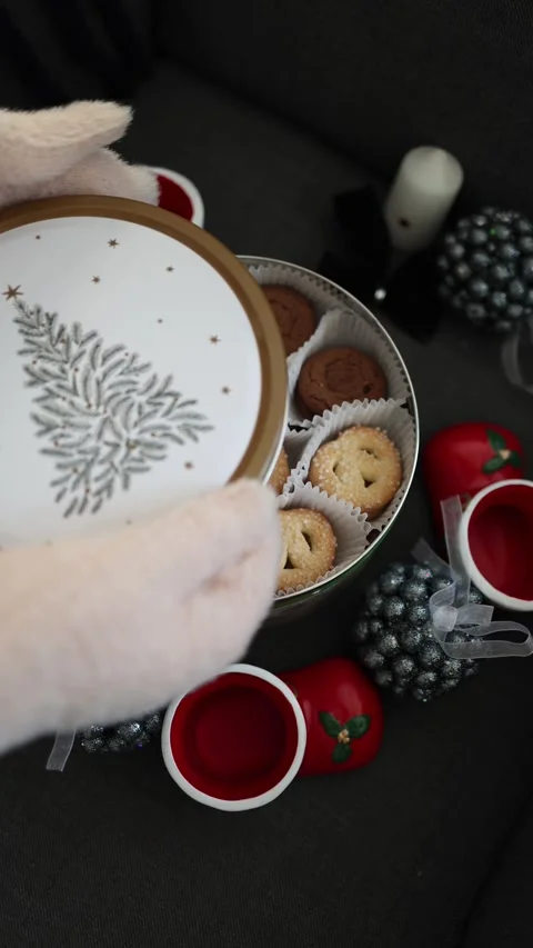 A festive scene featuring gloved hands holding a beautifully designed cookie tin Video stock 294701381