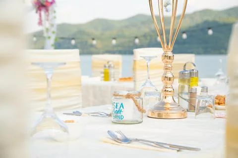 Festive serving table on the beach in sunny day. Preparing for an open-air pa Stock Photos