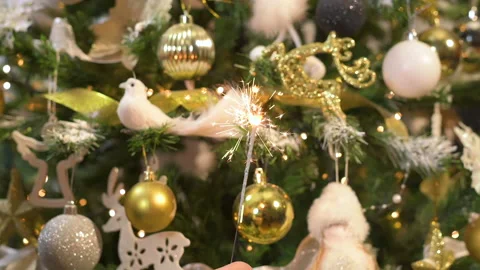 Festive sparkle burning in front of gold white Christmas tree. Slow motion Stock-Footage 166528874