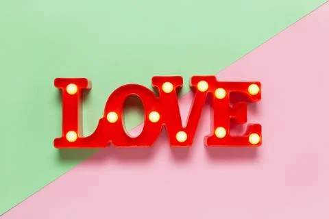 Festive spring flat lay. Red lamp in form of word Love with small bulbs on pa Stock Photos