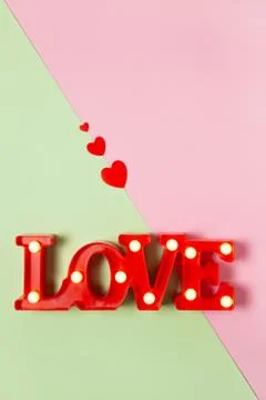 Festive spring flat lay. Red lamp in form of word Love with small bulbs on pa Stock Photos