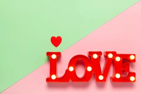 Festive spring flat lay. Red lamp in form of word Love with small bulbs on pa Stock Photos