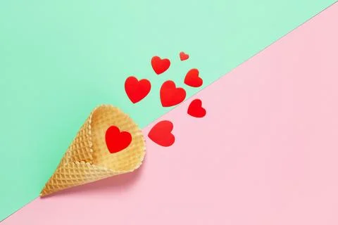 Festive spring flat lay. Red hearts in waffle cone on pastel pink and turquoi Stock Photos