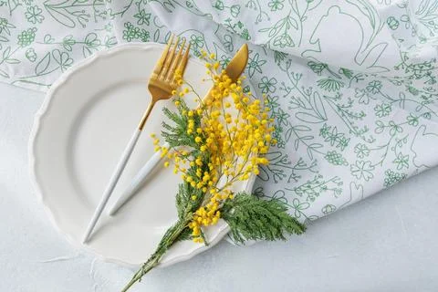 Festive spring table decor with mimosa flowers and gold cutlery Stock Photos