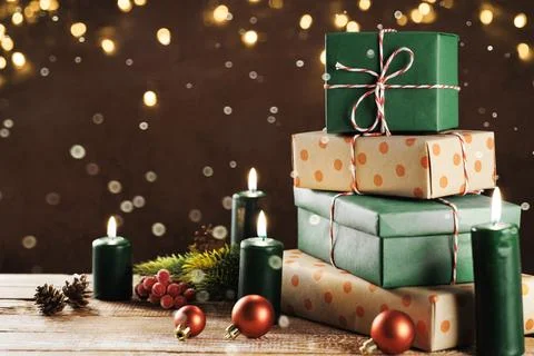 Festive stack of Christmas presents and candles on a wooden table Stock Photos