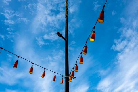 Festive string lights add color to a sunny outdoor setting during daytime in a v Stock Photos
