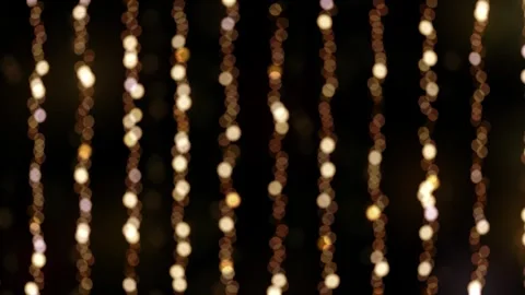 Festive string lights casting a warm glow on a black background Stock Footage 256428140
