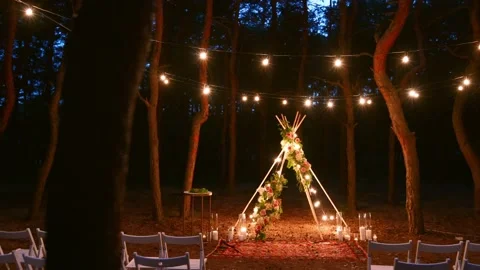 Festive string lights illumination on boho tipi arch decor on outdoor wedding Stock Footage 157212614