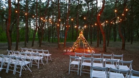 Festive string lights illumination on boho tipi arch decor on outdoor wedding Stock Footage 157259463