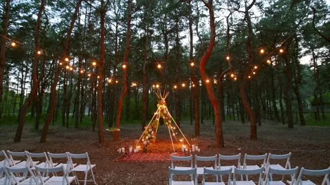 Festive string lights illumination on boho tipi arch decor on outdoor wedding Stock Footage 157327774