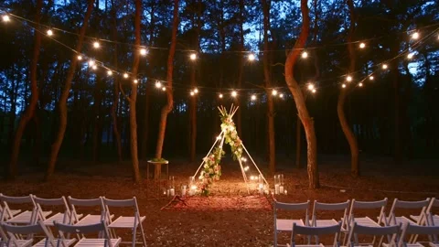 Festive string lights illumination on boho tipi arch decor on outdoor wedding Stock Footage 157328166