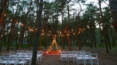 Festive string lights illumination on boho tipi arch decor on outdoor wedding Stock Footage 158196678