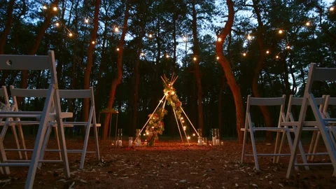 Festive string lights illumination on boho tipi arch decor on outdoor wedding Stock Footage 178375577