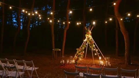 Festive string lights illumination on boho tipi arch decor on outdoor wedding Stock Footage 178376567