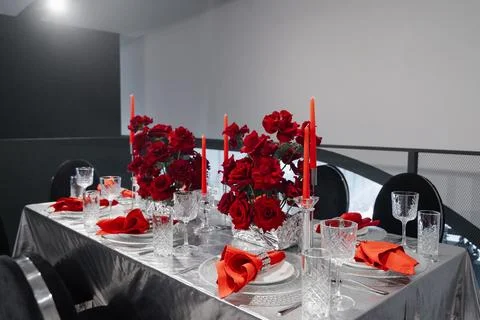Festive table for 6-8 persons decorated with red roses, candles, napkins Stock Photos