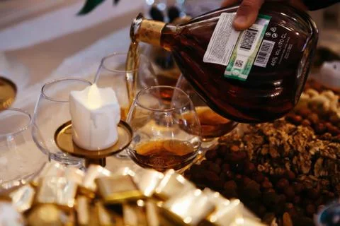 Festive table decorated with candles. hand pours cognac into a glass Stock Photos