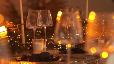 A festive table decorated with garlands and wine glasses. Wine glasses are place Stock Footage 324850665