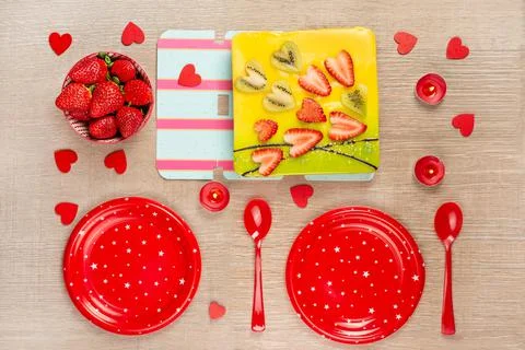 The festive table is served with red plates, candles, an appetizing cake cove Stock Photos