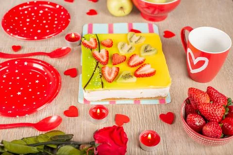 The festive table is served with red plates, candles, an appetizing cake cove Stock Photos