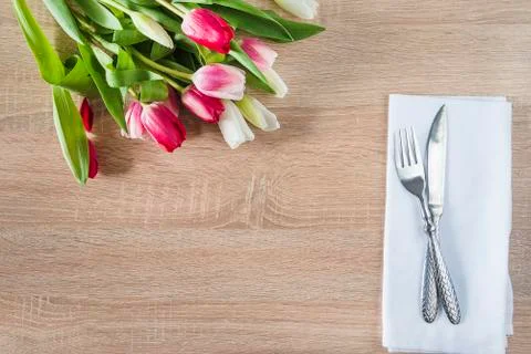 Festive table setting with bunch of purple tulips and forged fork and knife o Stock Photos