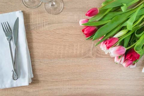 Festive table setting with bunch of purple tulips, forged fork and knife and  Stock Photos