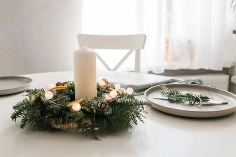 Festive table setting with elements of decorative green wreath and candles Stock Photos