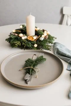 Festive table setting with elements of decorative green wreath and candles Stock Photos