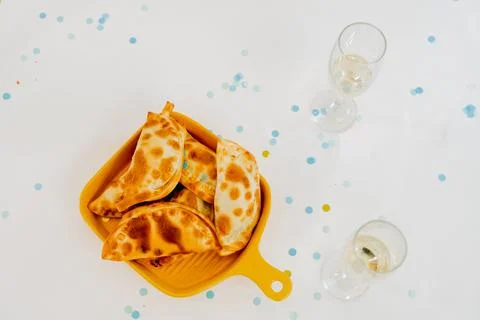 Festive table setting with empanadas, glasses and confetti Foto stock