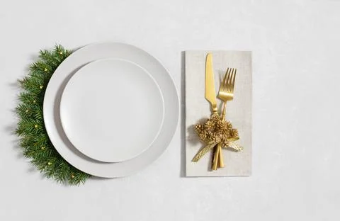 Festive table setting with empty beige plate, gold cutlery and fir branches.. Stock Photos
