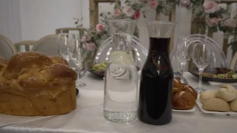 A festive table setting featuring traditional challah bread, water, and juice. 스톡 동영상 321189175