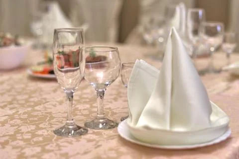 Festive table setting, folded napkin on a plate and three glasses for various Stock Photos