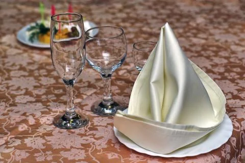 Festive table setting, folded napkin on a plate and three glasses for various Stock Photos