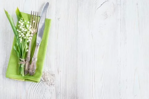 Festive table setting. Vintage fork and knife, bouquet of lilies of the valle Stock Photos