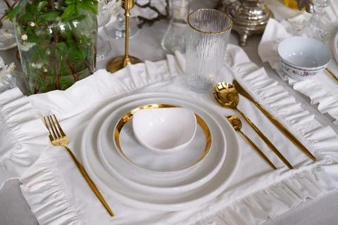 Festive table setting with white plates and gold cutlery on a white cotton .. Stock Photos
