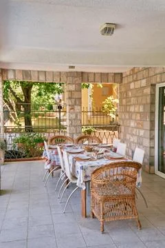 Festive table surrounded by chairs stands on the terrace of a stone villa Foto stock