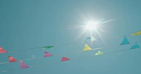 Festive triangular flags glow in the sunlight as they hang on strings beneath a Stock Footage 311236283