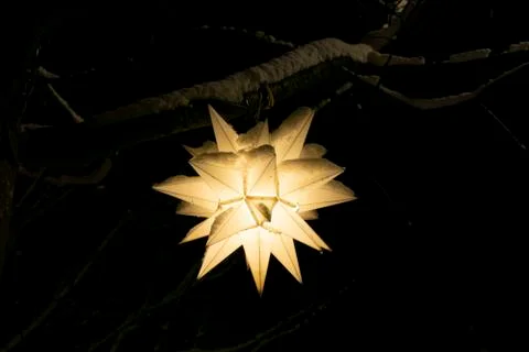 Festive winter tree lantern in the shape of a star glowing in the night. Stock Photos