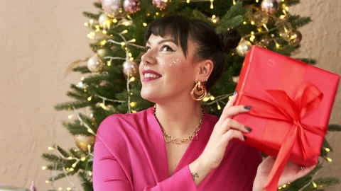 Festive woman shaking wrapped present gift box, christmas Stock Footage 166323628