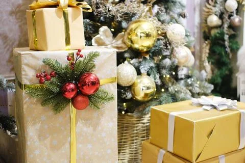 Festively wrapped gift boxes adorned with shiny ornaments and greenery, placed Photos