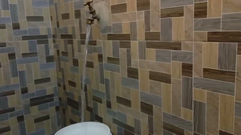 Fetching water from brass tap into white bucket in a bathroom. Stock Footage 314084815