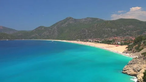 Fethiye Turkey beach shows turquoise sea, sandy bay, mountains - Coastal Resort Stock Footage 339820087