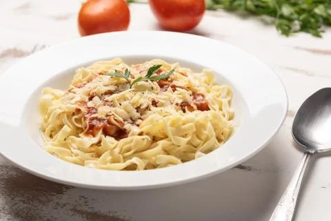 Fettuccine pasta with tomato sauce, parsley and basil in a white plate Stock Photos