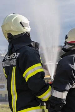 Feuerwehrmänner mit Druckschlauch löschen Brand Feuerwehrmänner in Sicherh Stock Photos